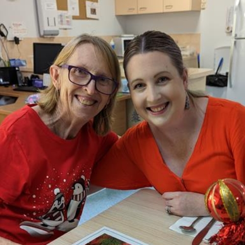 Nicole and her mum, Jennifer, are pulling each other in for a happy photo at a Christmas table together